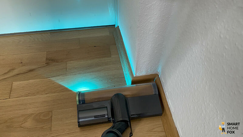 Die Dreame Z40 Station bei der Reinigung in einer engen Zimmerecke mit Blaulichtausleuchtung.